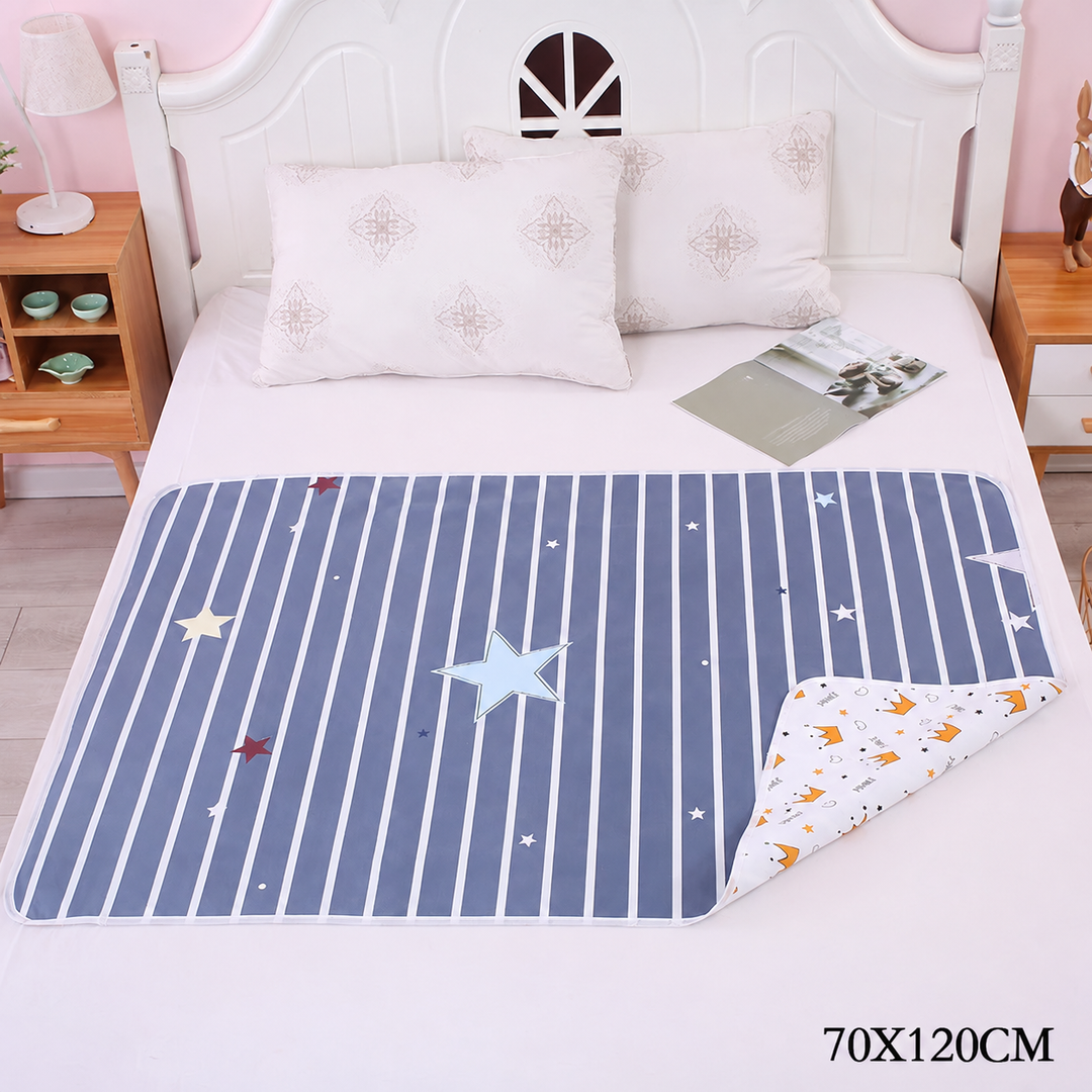 Navy star-and-stripe changing mat on a bed with one corner turned back, labeled 70 x 120 cm.