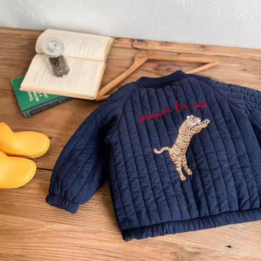 Back of the blue quilted jacket with tiger embroidery laid on a wooden table