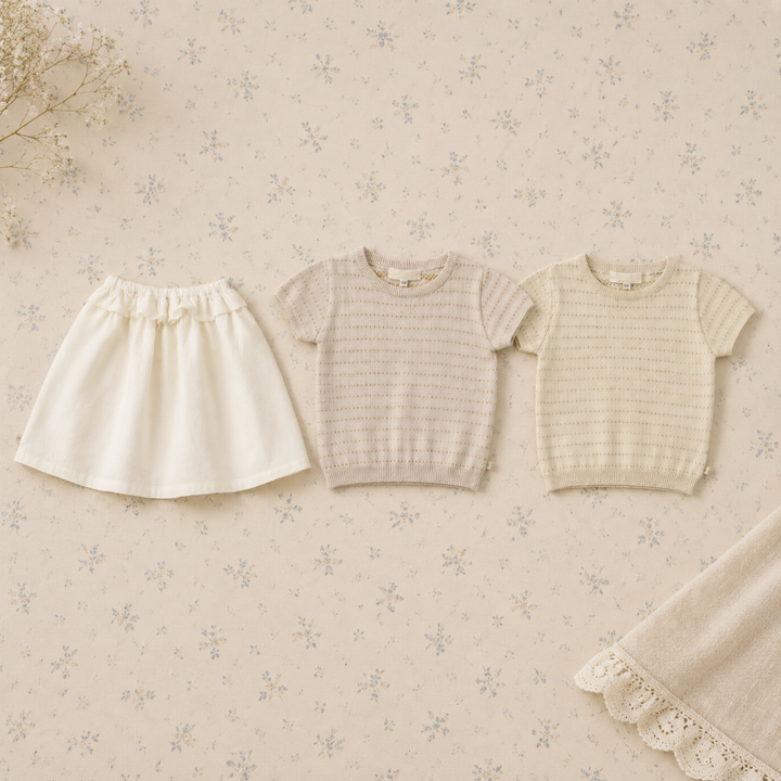 Two neutral short-sleeve knit tops arranged beside a white A-line skirt
