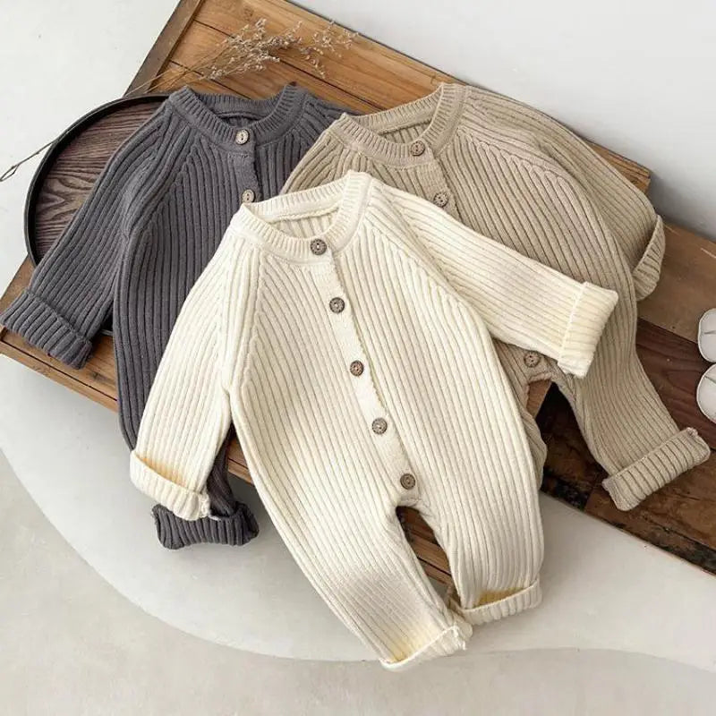 Cream, khaki, and gray ribbed baby rompers with long sleeves and front buttons arranged together