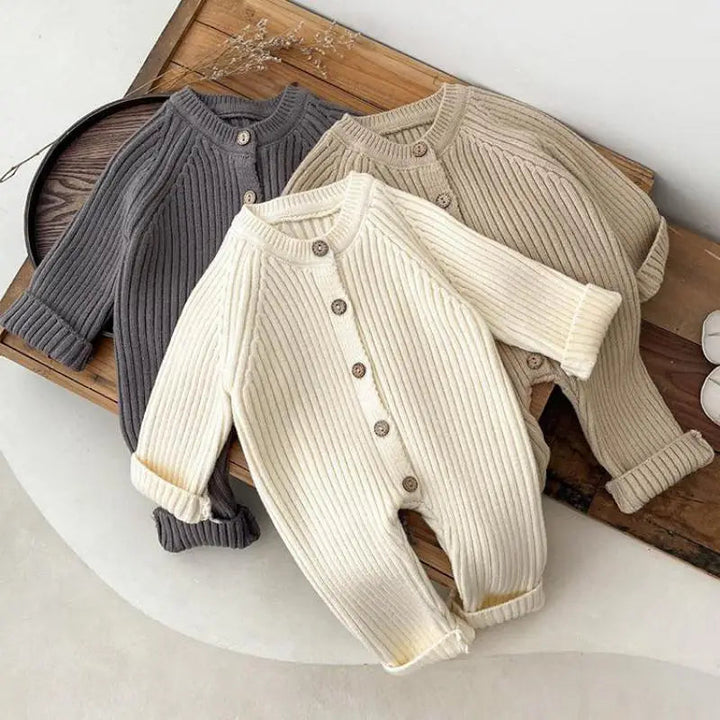 Cream, khaki, and gray ribbed baby rompers with long sleeves and front buttons arranged together