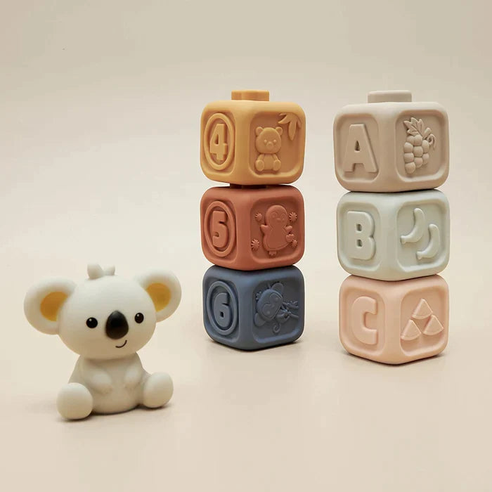 Two stacks of cubes with raised numbers and letters beside a koala figure