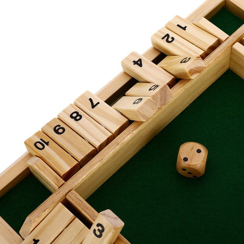Close-up of numbered wooden flaps and a die beside the green playing area