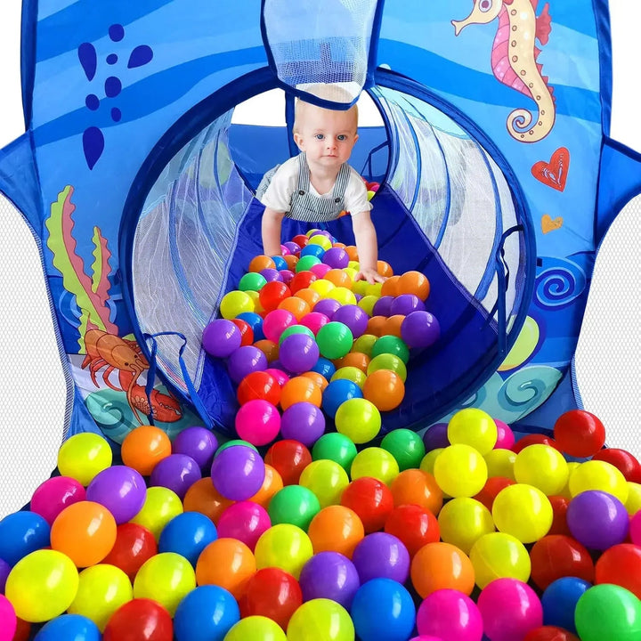 Close-up of a child in an ocean-print crawl tunnel with colorful play balls