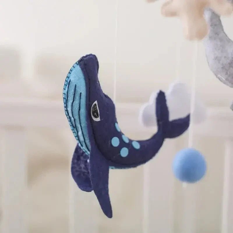 Close-up of a dark blue felt whale with stitched details and light blue spots on the Ocean mobile