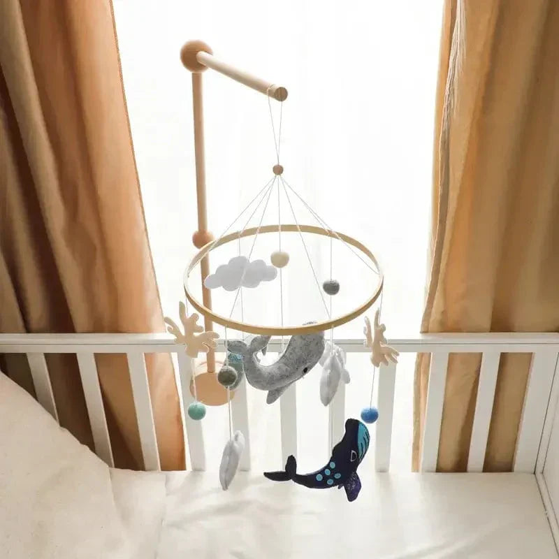 Overhead view of the Ocean baby mobile and wooden mounting arm above a crib