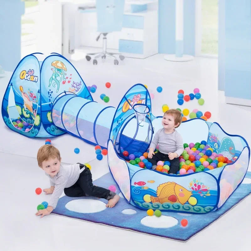 Two children playing with an ocean-print tent, crawl tunnel, and ball pit indoors