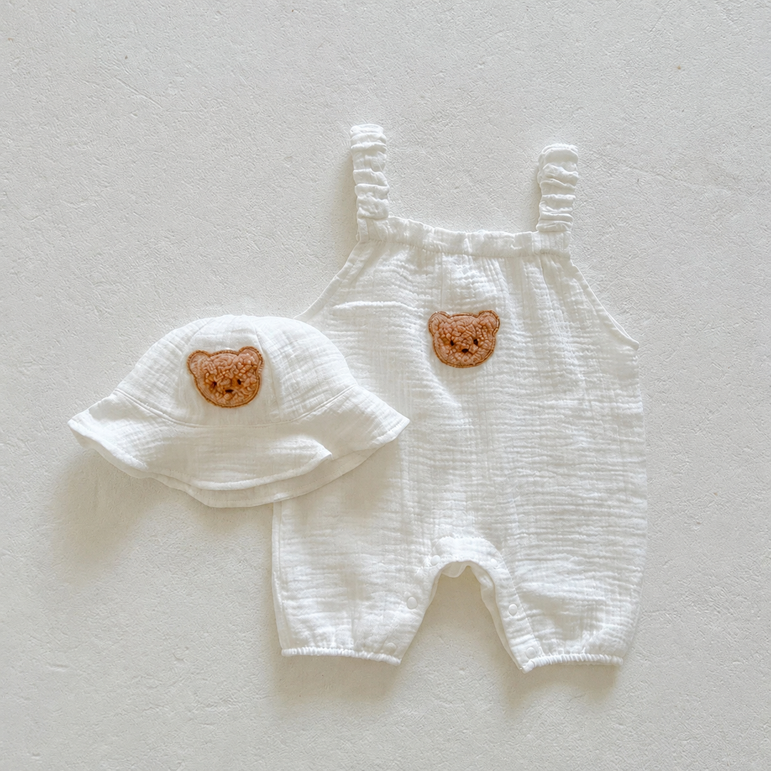 Off-white baby overalls and matching bucket hat with bear patches, laid flat