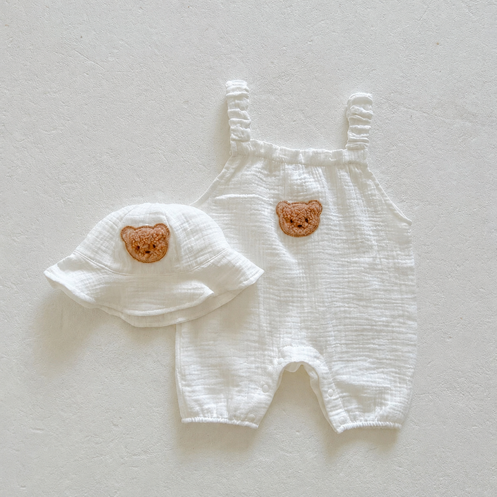 Off-white baby overalls and matching bucket hat with bear patches, laid flat