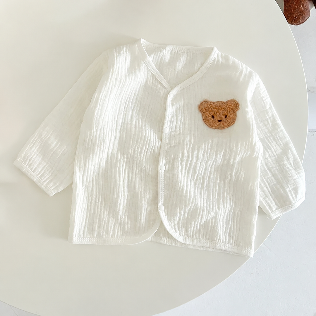 Off-white long-sleeve baby top with crinkled fabric and a bear patch