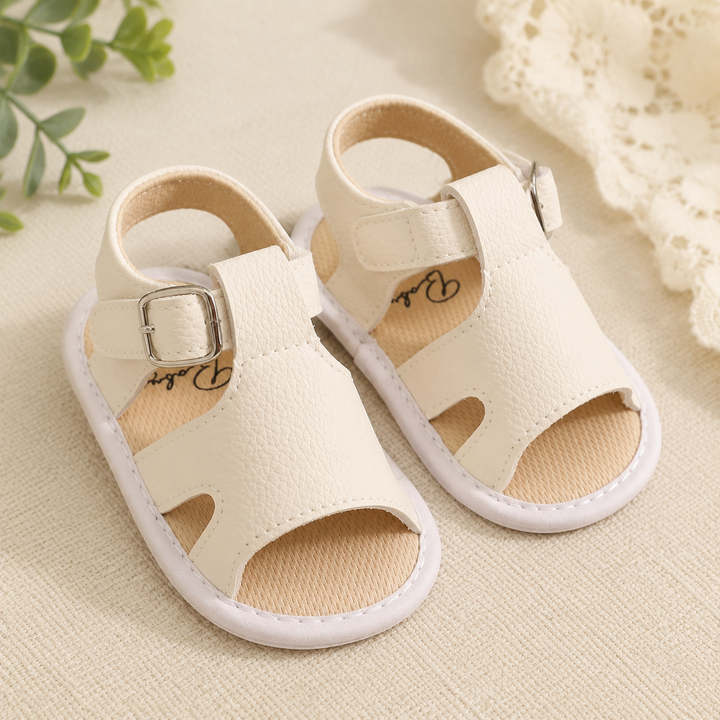 Pair of off-white baby buckle sandals with open toes and side cutouts