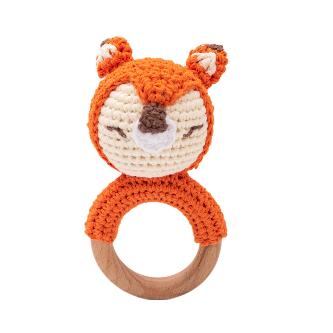 Orange crocheted fox baby rattle with a white face and wooden ring