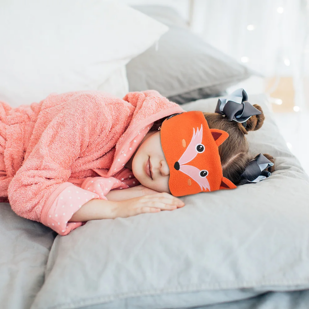 Child lying on a couch while wearing the orange fox Bluetooth sleep mask.