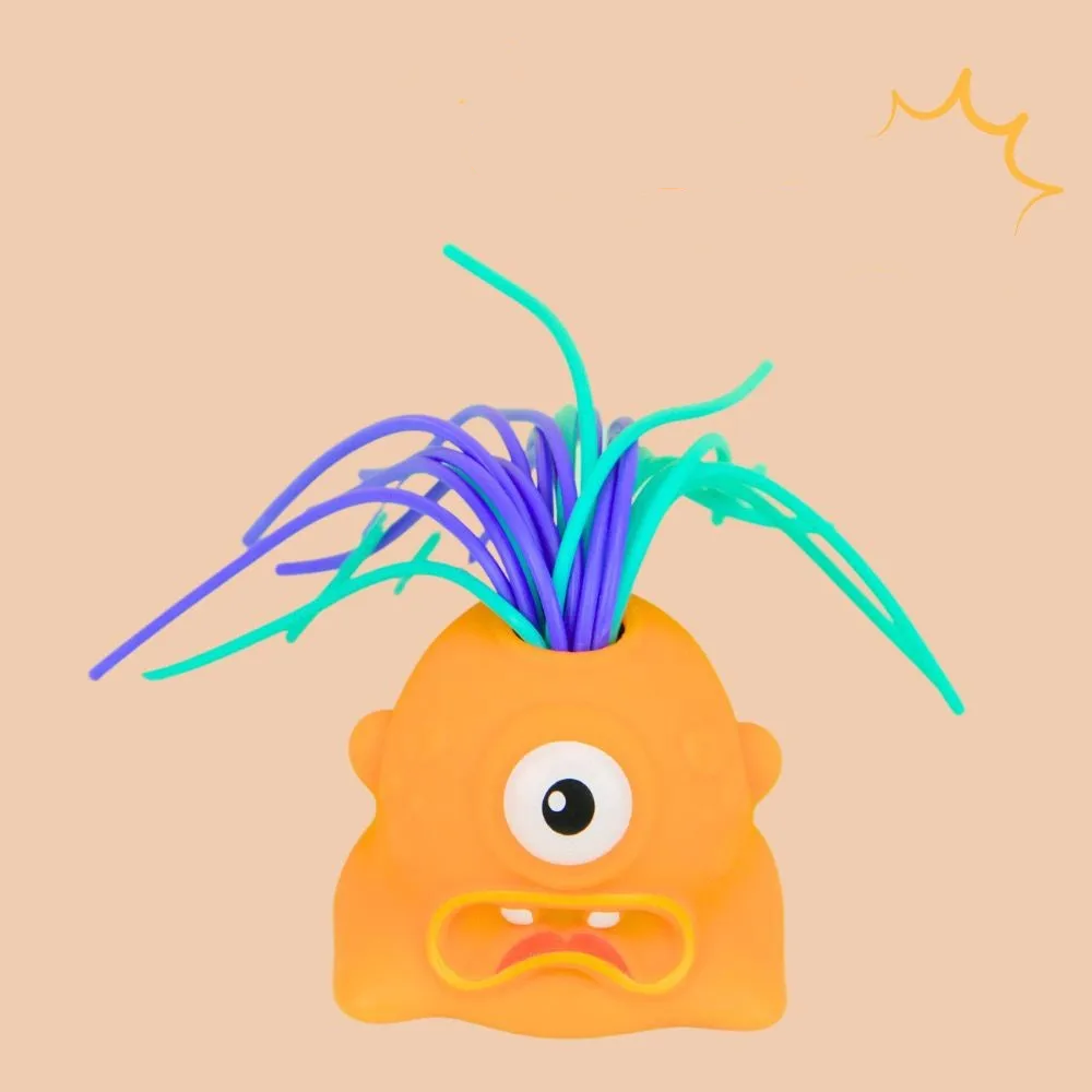 Orange one-eyed monster stress toy with a frowning mouth and colorful hair