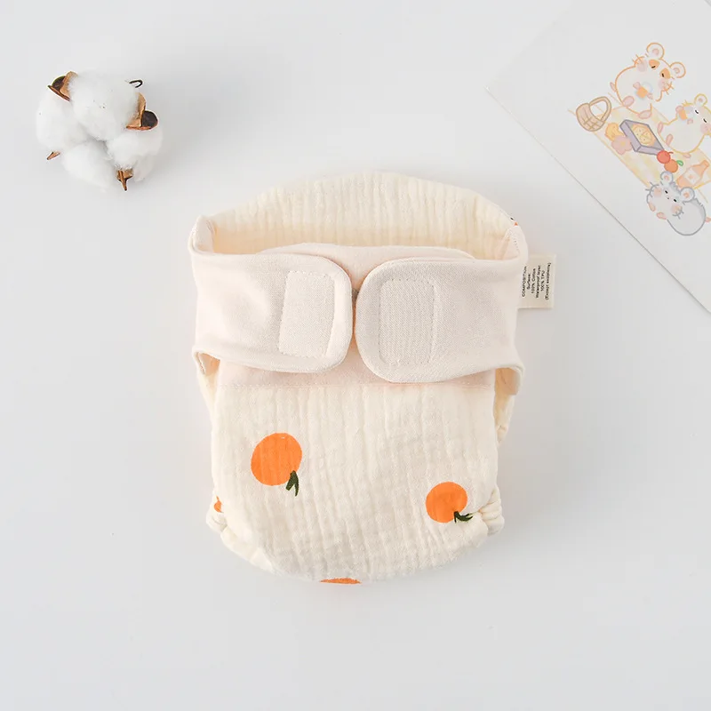 Cloth diaper with bright orange fruit prints and a cream waistband