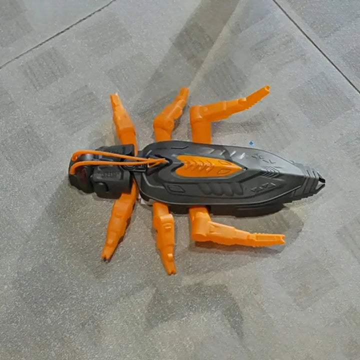 Orange insect-style robot toy resting on a gray surface