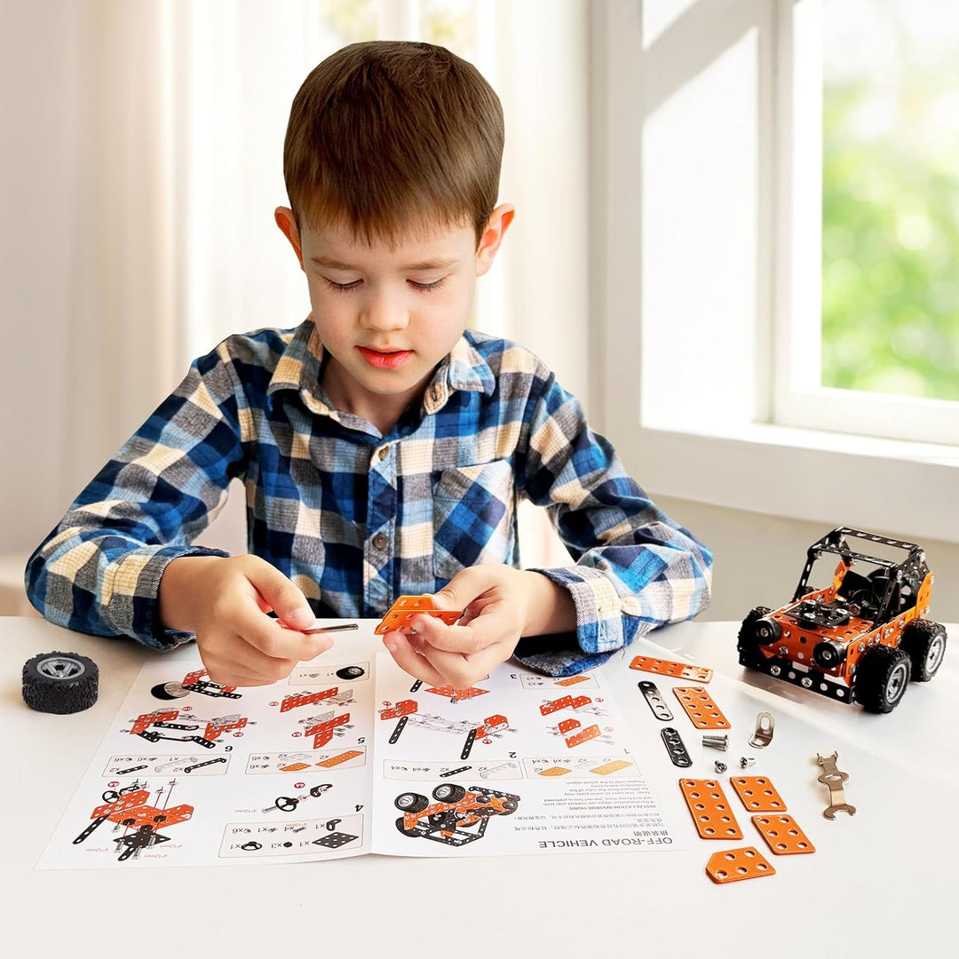 Child assembling an orange off-road vehicle model beside instructions, wheels, and metal parts