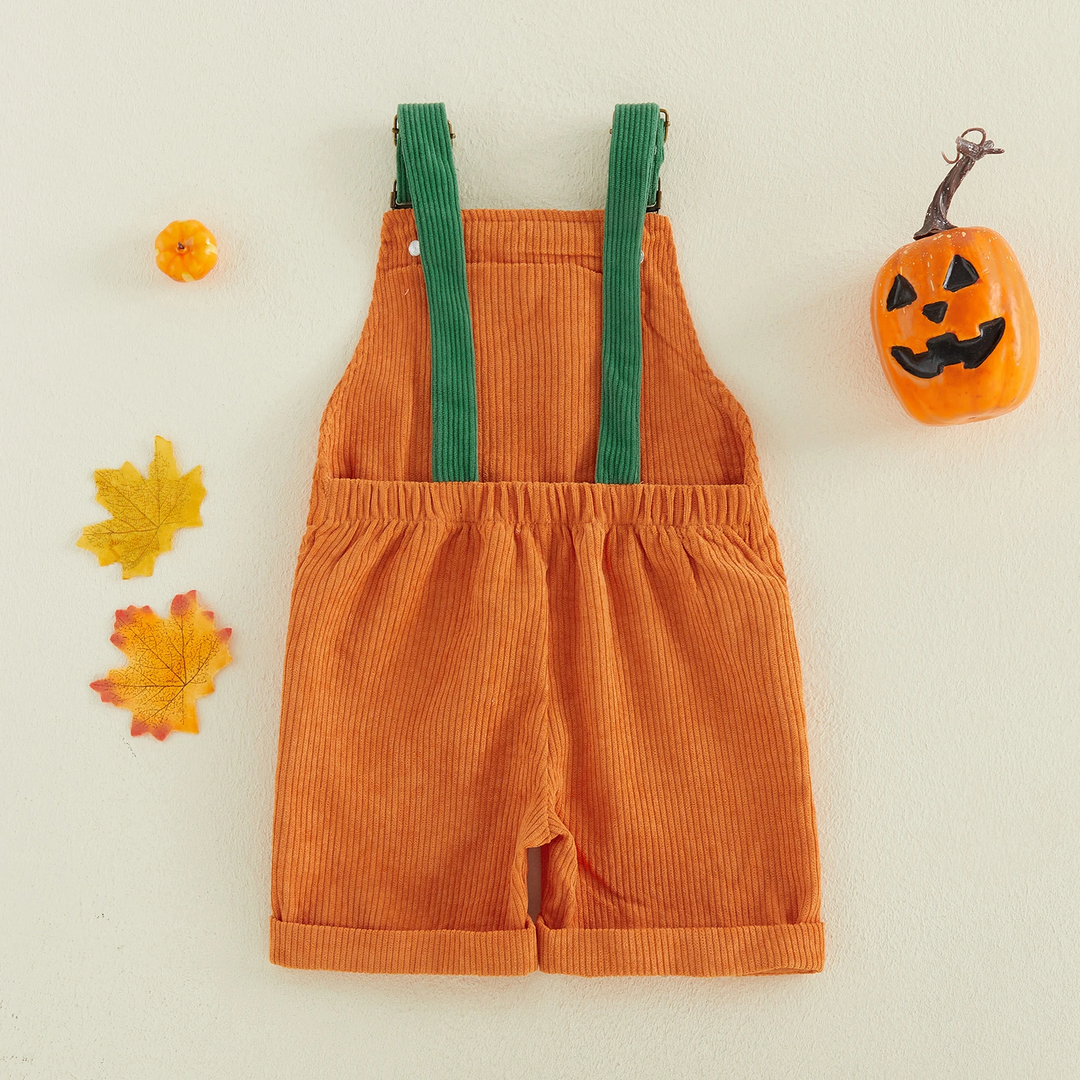 Back view of orange pumpkin overalls with green straps, a gathered waist, and cuffed short legs.