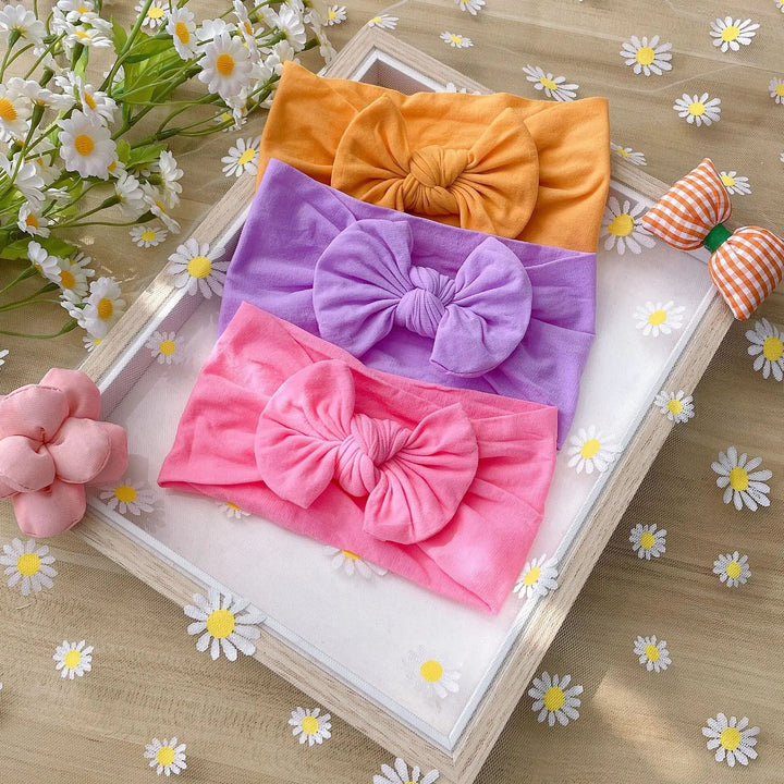 Orange, purple, and bright pink bow headbands displayed together