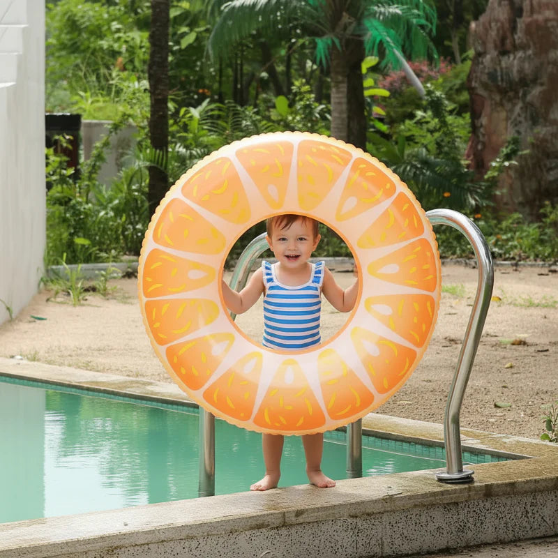 Child holding an orange-slice swim ring next to a pool ladder.