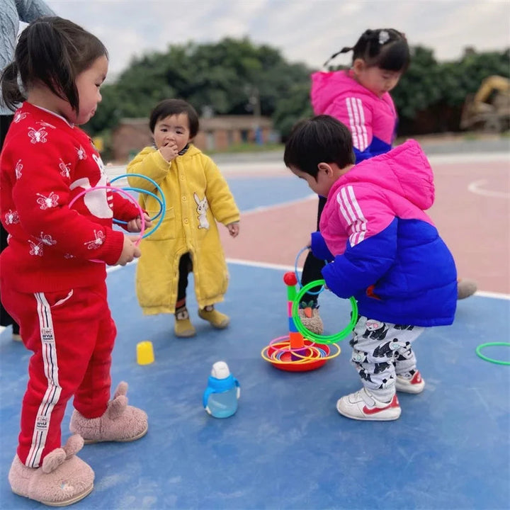Children playing with ring toss towers and colorful rings outdoors