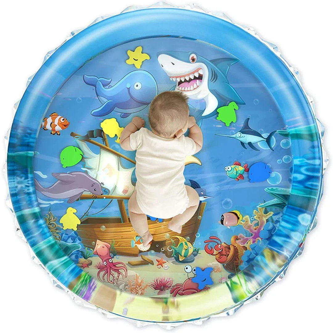Overhead view of a baby lying on a blue water mat with sea creatures and floating shapes