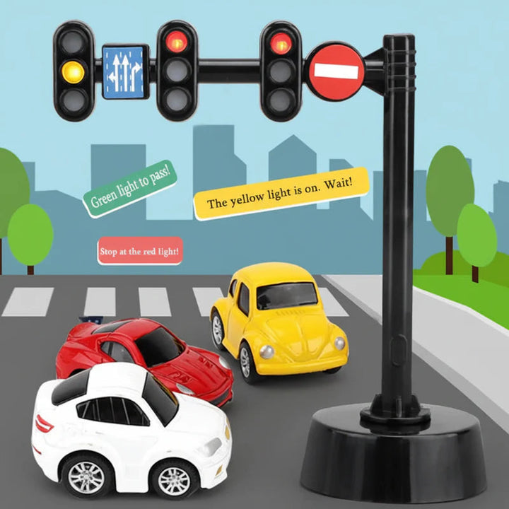 Three-signal overhead traffic light with road signs beside small toy cars.