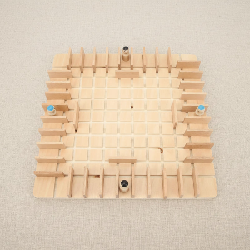 Top view of a wooden grid board with four pawns and upright barriers