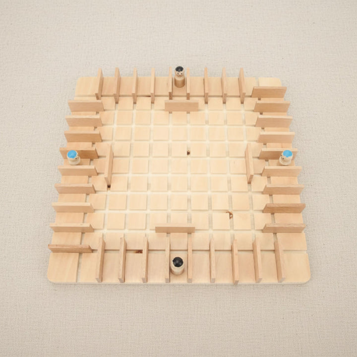 Top view of a wooden grid board with four pawns and upright barriers