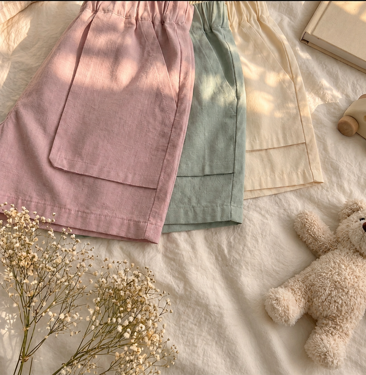 Overlapping pink, sage green, and light beige shorts showing their large front patch pockets.