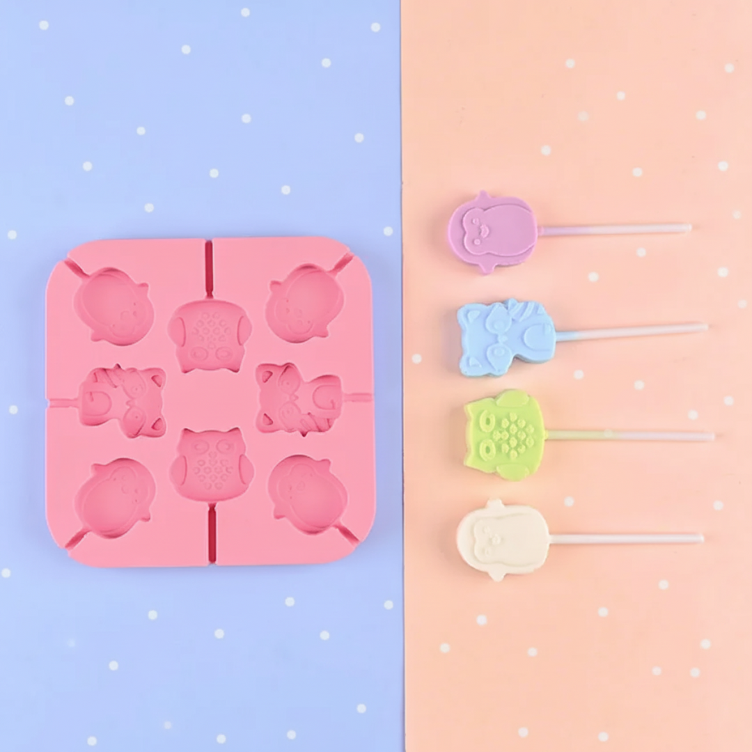 Pink lollipop mold with owl and other animal cavities beside pastel treats