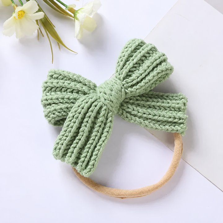 Pale green knitted bow headband with ribbed loops and bow tails
