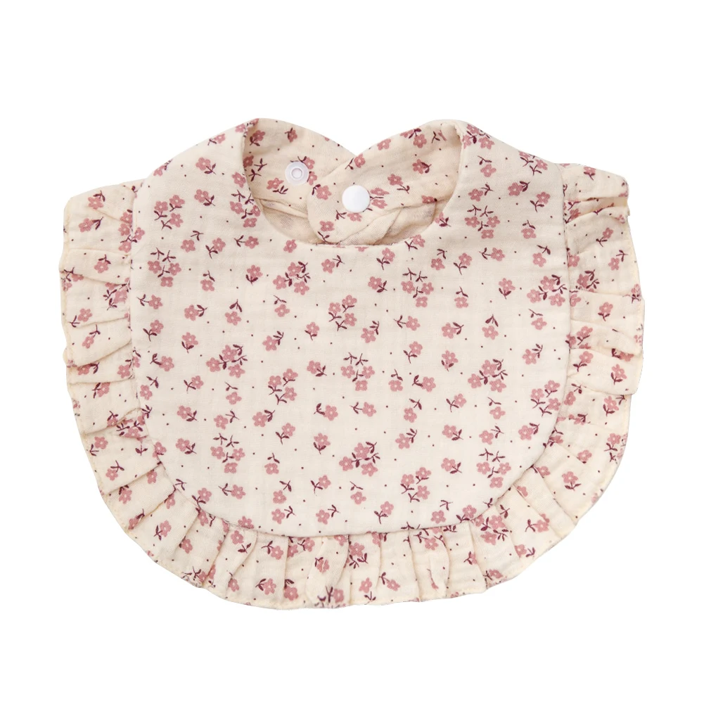 Pale pink cotton baby bib with small pink floral clusters and ruffled edging