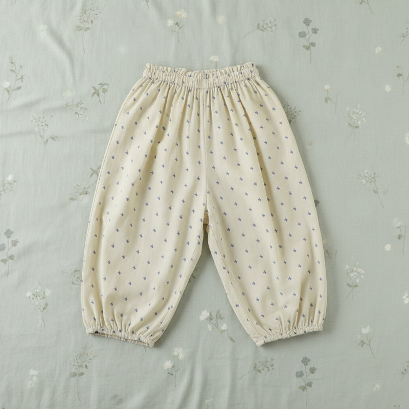 Pale yellow harem pants with small blue motifs, an elastic waist, and gathered cuffs.
