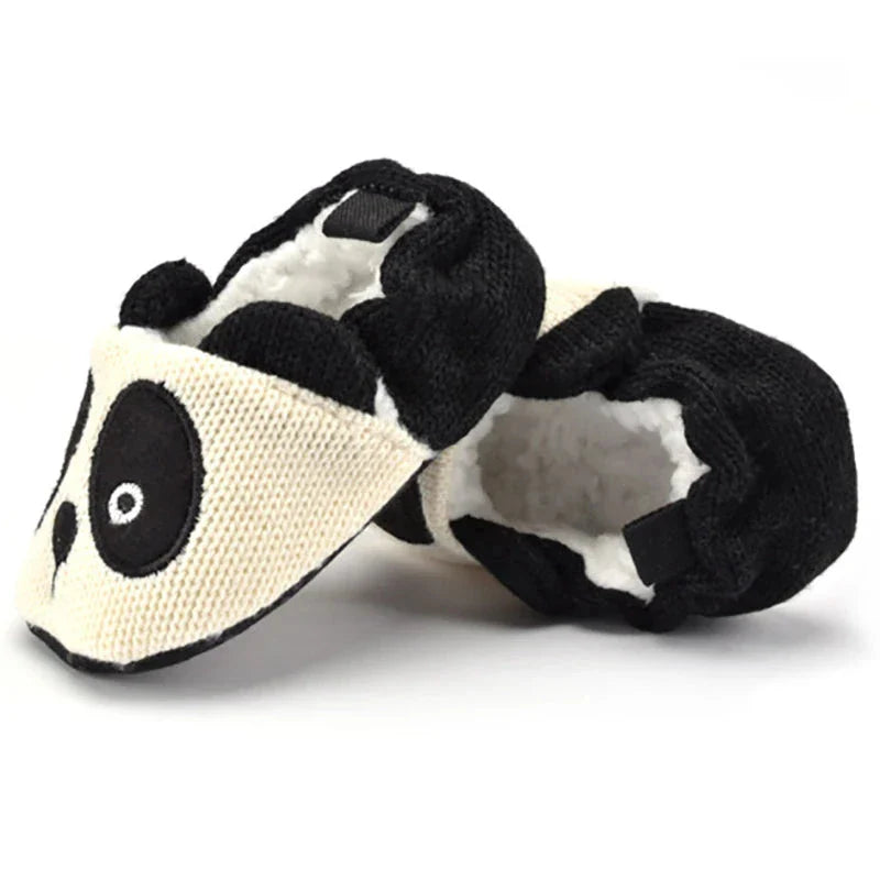 Black-and-white panda baby slippers with fluffy lining visible inside the heel openings