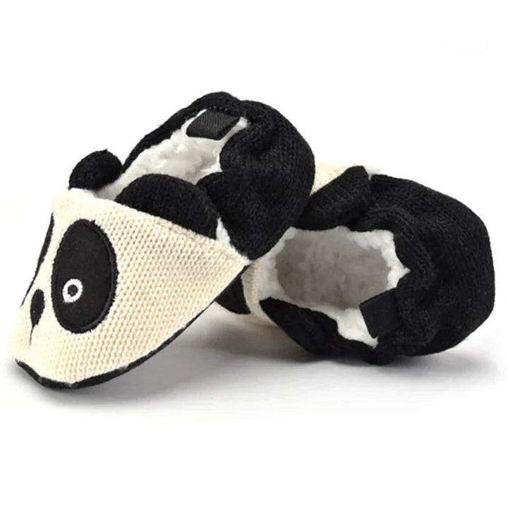 Black-and-white panda baby slippers with fluffy lining visible inside the heel openings