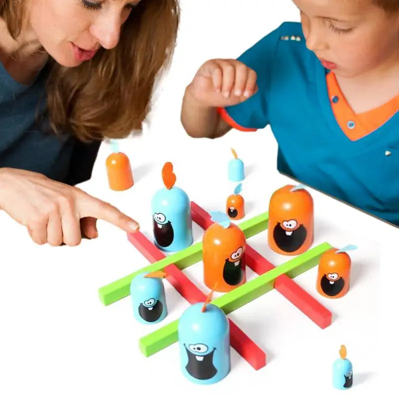 An adult and child play tic-tac-toe with blue and orange pieces on a red and green grid.