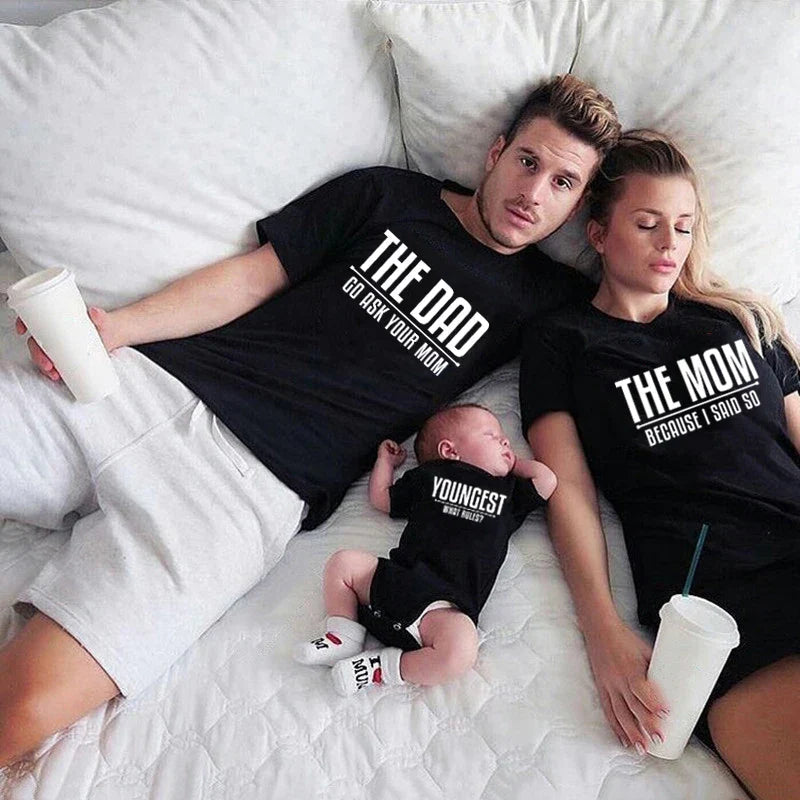 Parents and a baby wearing matching black tops labeled Dad, Mom, and Youngest.