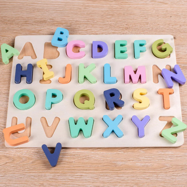 Pastel uppercase letter puzzle with loose pieces arranged on and around the wooden board