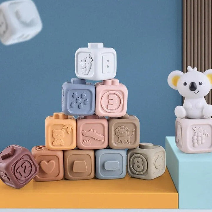 Pastel stacking cubes with raised numbers, shapes, and animals beside a koala figure