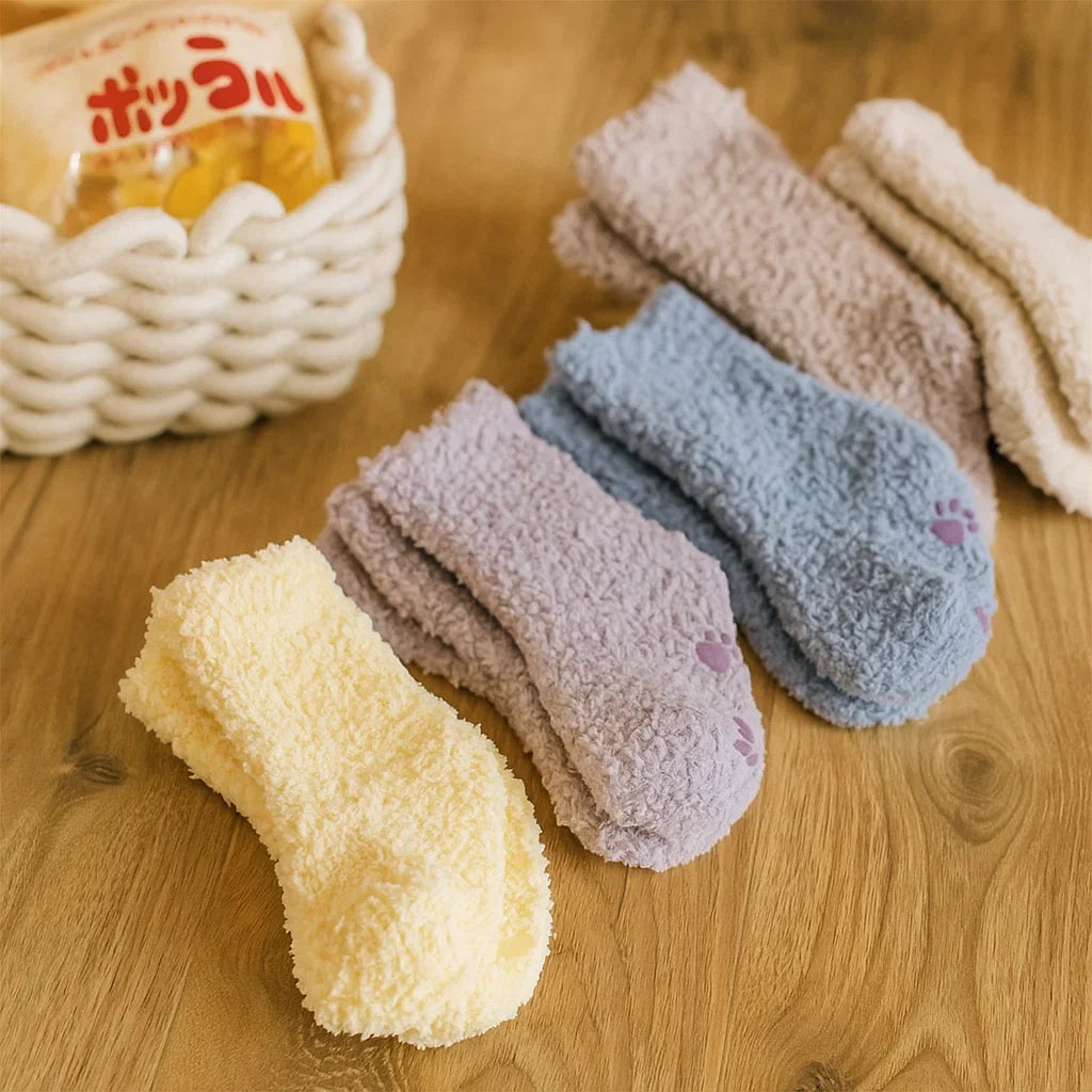 Fleece socks in pastel and neutral colors arranged across a wooden table.