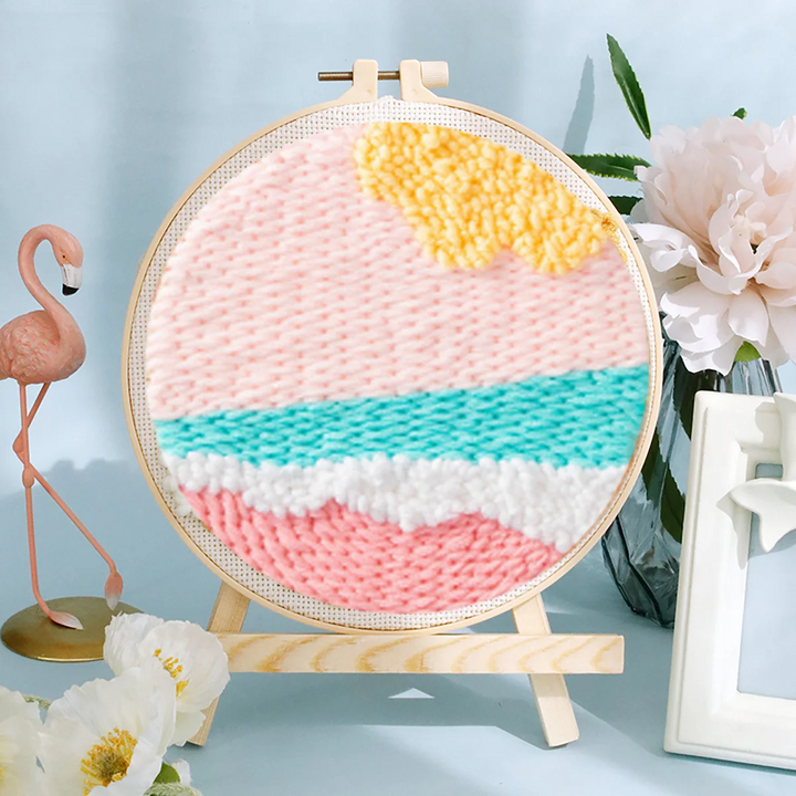 Pastel ocean punch needle hoop with a yellow sun, pink sky, and turquoise and white waves