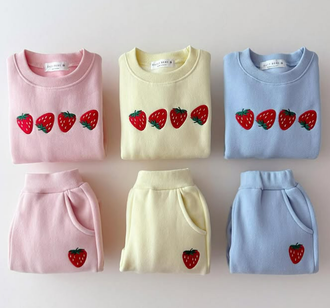 Folded strawberry sweaters and matching pants in light pink, light yellow, and light blue