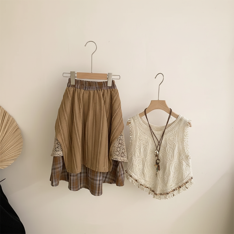 Back of the brown patchwork skirt beside the cream sleeveless crochet top on hangers