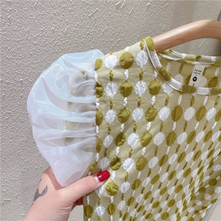 Close-up of the patterned green-and-white top and sheer white puff sleeve
