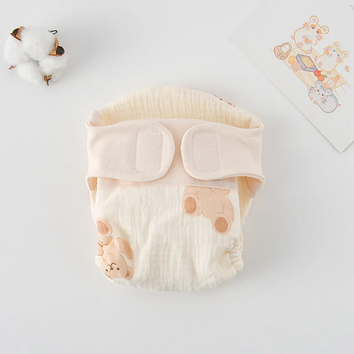 Cloth diaper with pale peach bear illustrations and cream fastening tabs