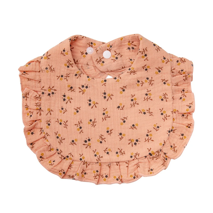 Peach-colored cotton baby bib with small floral sprigs and ruffled edging