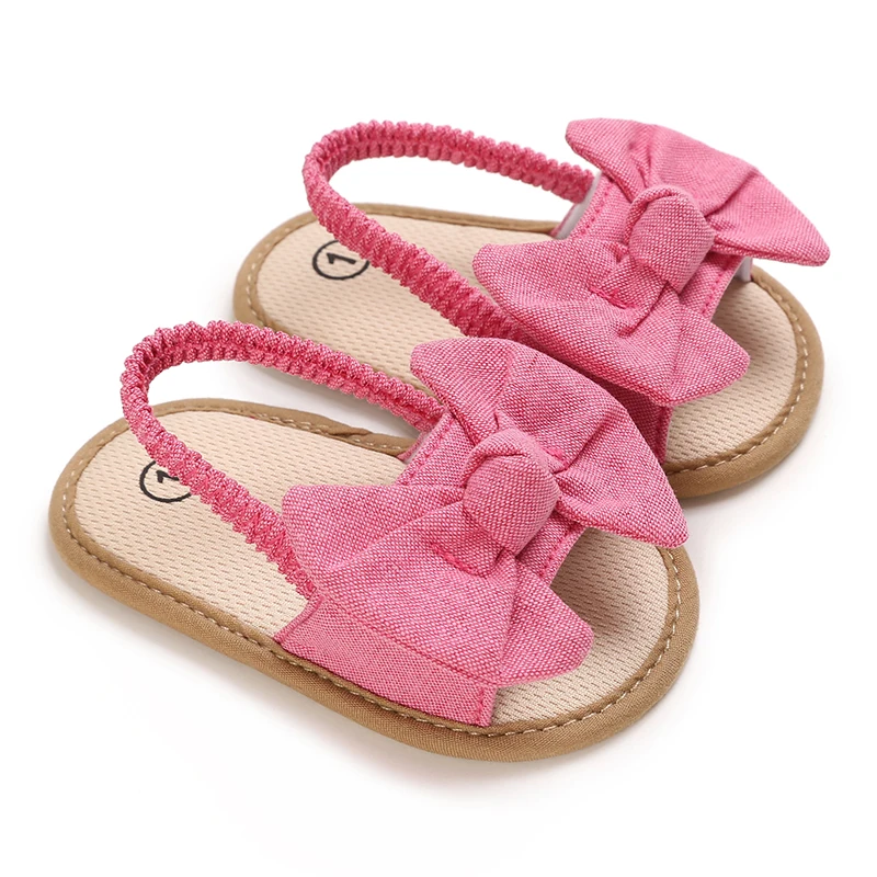 Peach-pink baby sandals with matching fabric bows and elastic heel straps