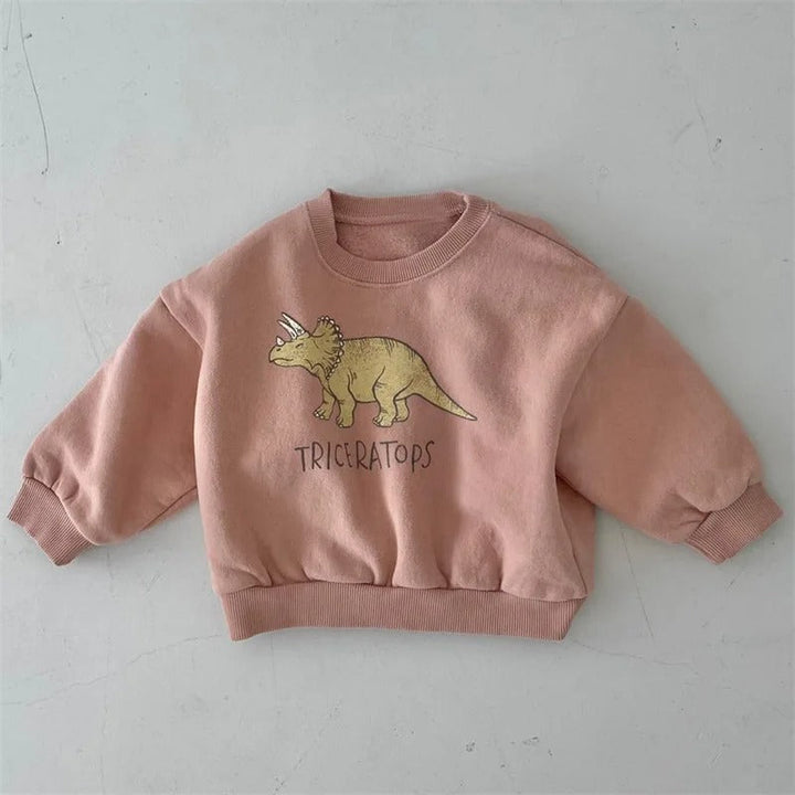 Peach-pink crewneck sweatshirt with a yellow triceratops graphic and ribbed cuffs
