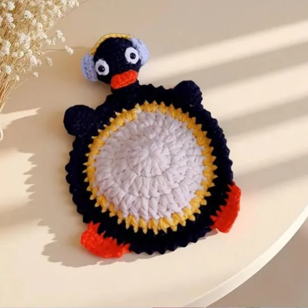 Penguin coaster with a pale belly, dark outline, yellow trim, and orange feet